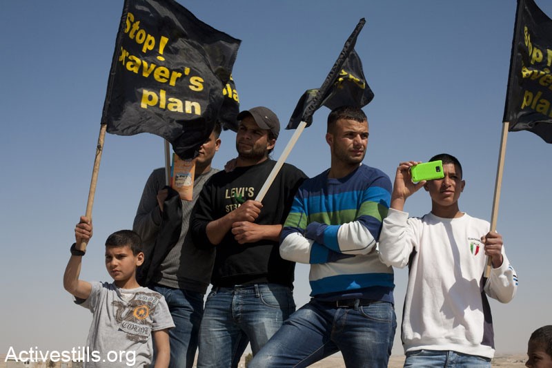 Arab-Bedouins and other activists participating in a vigil to mark Land Day in the unrecognized village of Wadi El Naam, Israel, on March 30, 2012. During the vigil the protesters held signs calling to stop Prawer Plan, approved by the Israeli government on the 11th of September, 2011. The plan will displace more than 40,000 Arab-Bedouin citizens through the destruction of most unrecognized Bedouin villages in the Negev desert (Photo: Activestills)