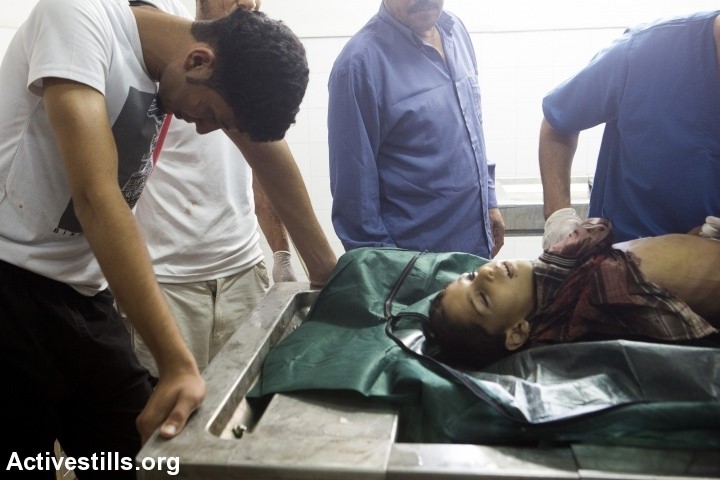 Palestinians identify the body of a child killed in Israeli attacks, at Al Shifa Hospital, Gaza City, July 30, 2014 (Photo: Activestills)