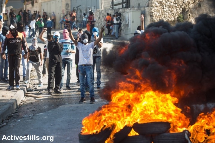 Palestinian youth has seen burning tires during demonstrations against occupation in the neighborhood of Issawia on October 24, 2014 in occupied East Jerusalem (Photo: Activestills)