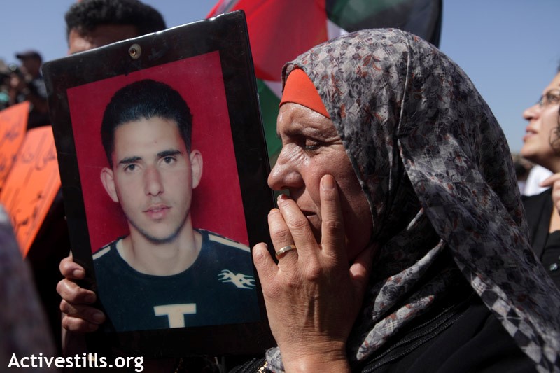 A woman carries a picture of her imprisoned son during a demonstration in support of the Palestinian prisoners’ hunger strike opposite the "Ofer" military court and prison, Bitunya, October 2011 (Photo: Activestills)