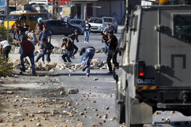 Palestinians from the al-Jalazone Refugee Camp clash with Israeli forces at the entrance the Jewish-only settlement of Beit El near Ramallah on Oct. 24, 2014.