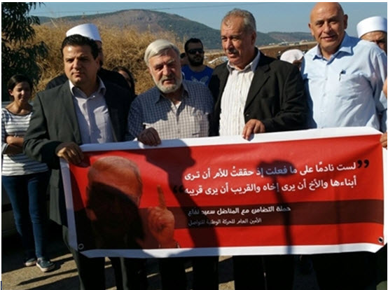 Protesters demonstrate for the release of Said Nafaa outside the Gilboa prison on Sunday, November 1, 2015. The banner, displaying a portrait of Said Nafaa and quoting him, reads: "Not regretting what I have done if I have achieved a mother's being able to see her children, and a brother his brother, and a family member his relative." First from left: Joint List chairman, MK Ayman Odeh (Hadash); third from left: Chairman of Israel’s Higher Arab Monitoring Committee and former Hadash MK Mohammed Barakeh. 