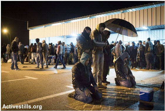 Palestinian workers pray after crossing into Israel via the Eyal checkpoint, near the occupied West Bank city of Qalqilya