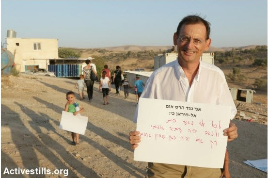 Hadash MK Dov Khenin (Joint List) during a demonstration against eviction of the Arab-Bedouin village of Atir-Umm al-Hiran. The sign held by MK Khenin reads (in print): “I oppose the destruction of Umm al-Hiran because:” and continues in handwriting: “every child deserves a home and the Negev will only have a real future if there will be true equality here.”