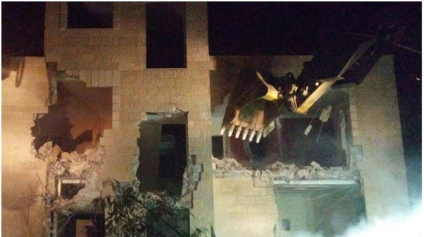 Secured by armed Israeli forces, a bulldozer destroys one of a 20 Palestinian homes demolished in occupied East Jerusalem on Monday night, July 25.