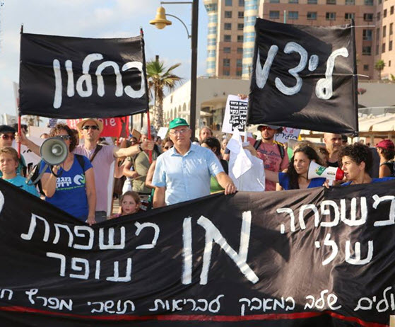 A demonstration in Haifa against air pollution from privatized Oil Refineries group. The banner reads: "My family OR the Ofer Family - We're escalating the struggle for the health of the residents of the Haifa Bay."