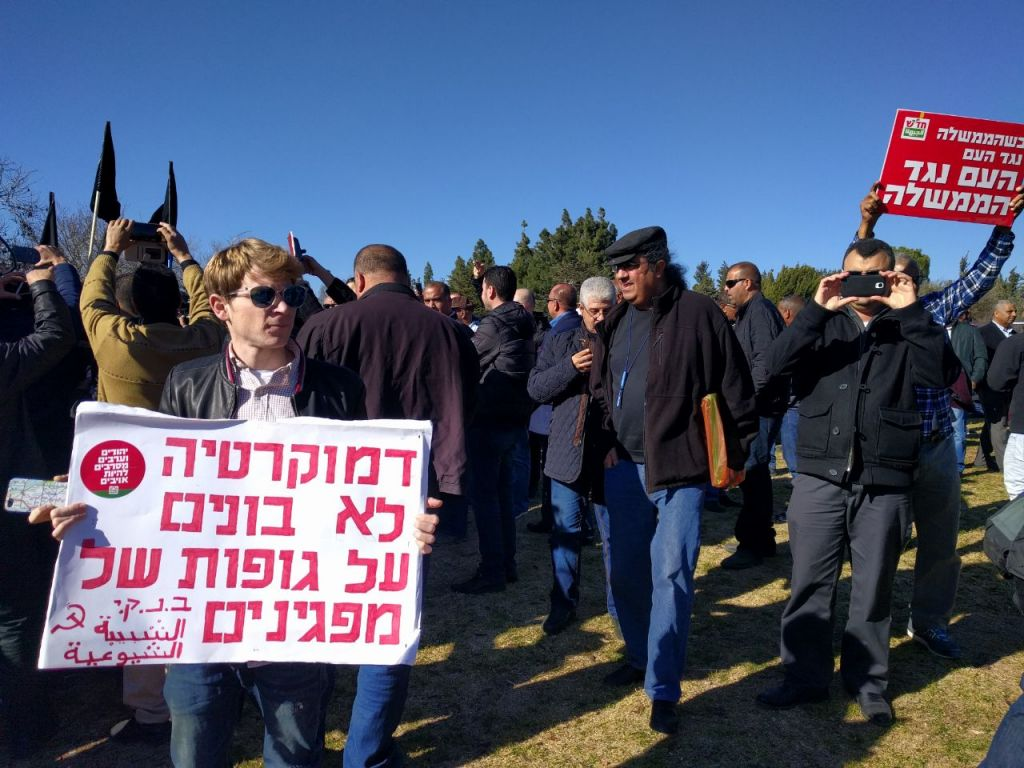 A Communist Party of Israel activist holds a Young Communist League sign reading, 'Democracy isn’t built on the bodies of dead protesters,' during the demonstration against demolitions of Arab homes in front of the Knesset in Jerusalem, Monday, January 23, 2017
