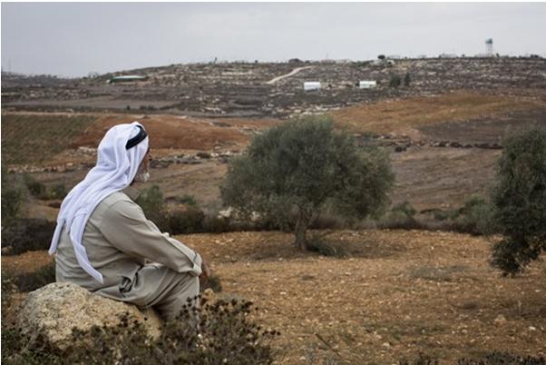 A Palestinian farmer viewing the outpost settlement of Adei Ad