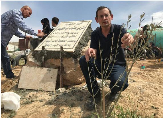 Hadash MK Dov Khenin in the Arab-Bedouin village of Umm al-Hiran in the Negev Desert on this year’s Land Day, kneels by an olive tree planted next to the memorial built to commemorate Yacoub Abu al-Qee’an, shot dead by Israel police in the course of a home demolition operation conducted there on January 18, 2017.