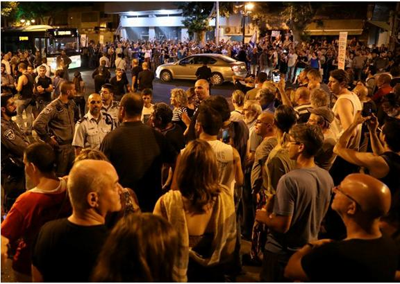 Demonstrators gather outside of the Petah Tikva police station on Saturday night, August 19.