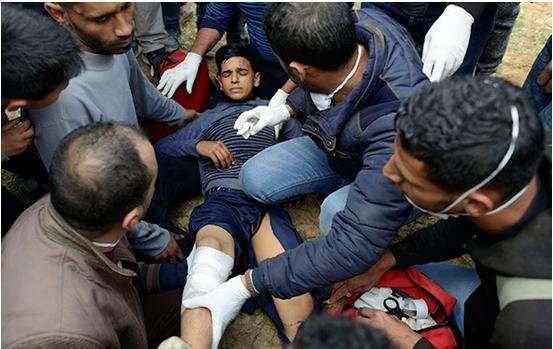 Palestinians tend to a boy who was shot in the leg by an Israeli sniper during the Great Return March in Gaza, east of the Jabaliya refugee camp, March 30, 2018.
