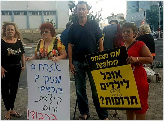 MK Khenin with protesters in Tel Aviv on Thursday, May 31. The placard to the left reads: “Senior citizens demand: Stipend that allows living honorably!”; to the right” “What will you choose this month? Food for children or medications?”