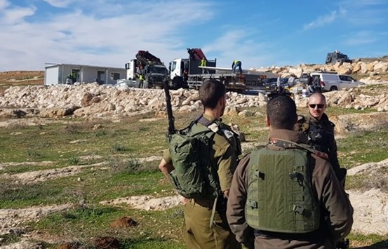 Three armed Israeli soldiers of occupation, among others, "secure" the site during the demolition of what was to be the new "al-Tahadi 13" school, in the background, south of Hebron on Wednesday, December 5. The elementary school was to have opened its doors today, December 7, to 50 Palestinian pupils. (Photo: Ma'an)