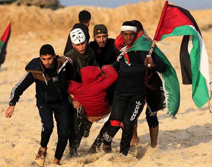 A Palestinian youth wounded by Israeli forces along the Gaza border is evacuated by other young protestors. 