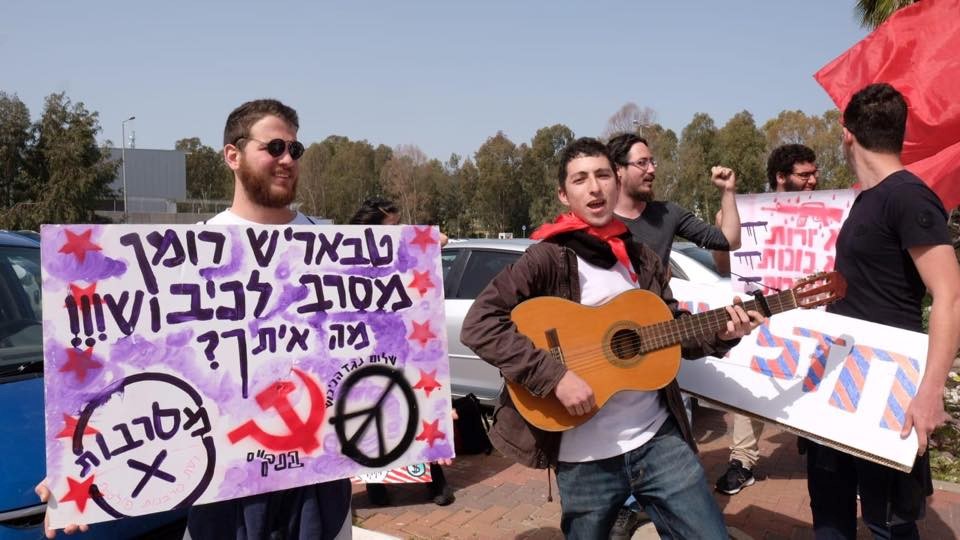 Roman Levin (with guitar) and comrades demonstrate outside the military base at Beit Naballah. The Hebrew placard to the left reads: "Tbarish ('Friend' ['Comrade'] in Russian), Roman rejects the occupation!!! What about you?"
