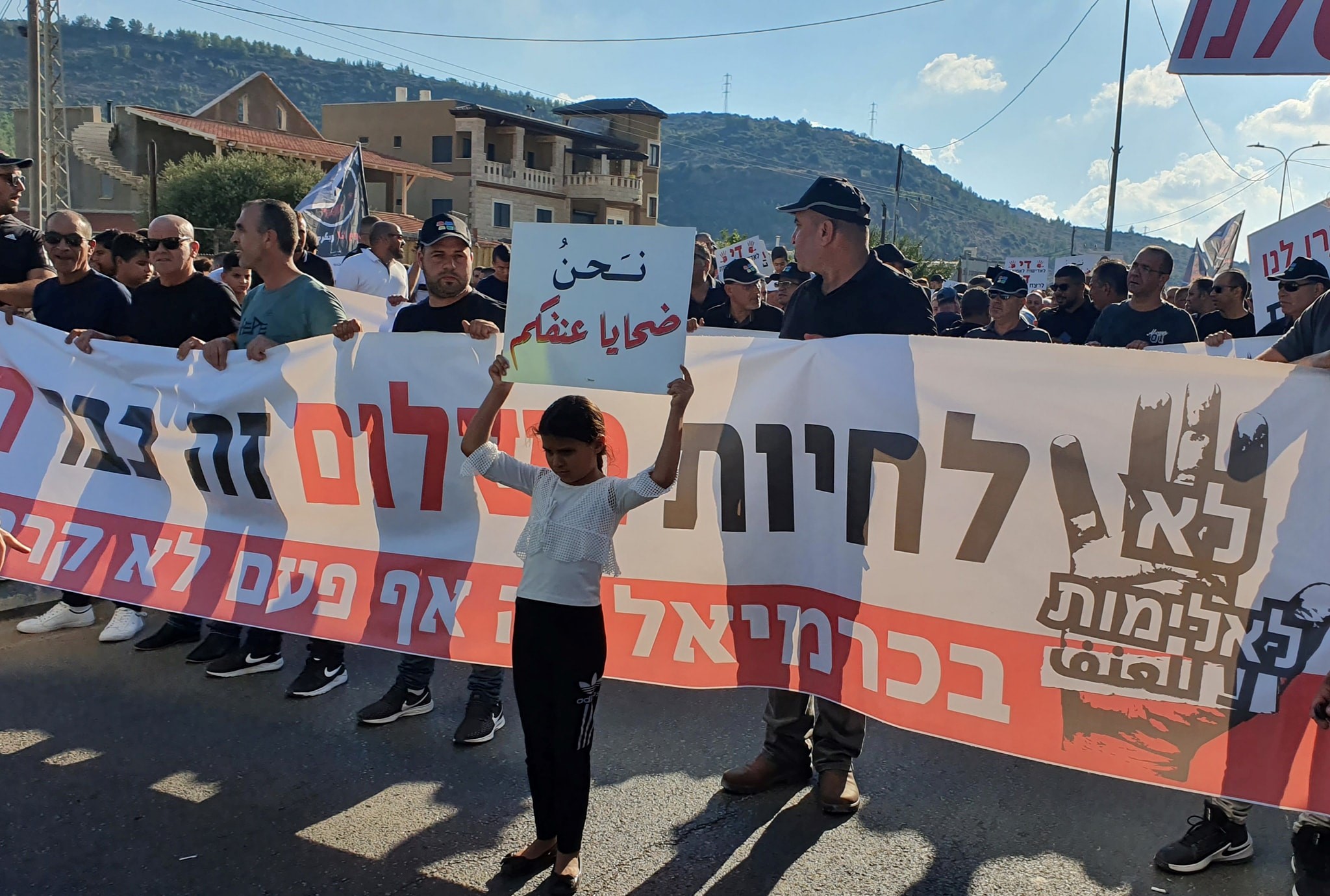 Demonstrators marching in the Upper Galilee town of Majd al-Krum on Thursday, October 3, to protest rampant gangland violence in Israel's Arab communities and police inaction in combating it; the large banner reads (in Hebrew): "No to Violence – To live in peace has become a dream... In Karmiel [a neighboring, primarily Jewish city just to the east of Majd al-Krum] this has never happened."Before the banner, a young girl holds aloft a sign in Arabic reading: "We are victims of your violence."