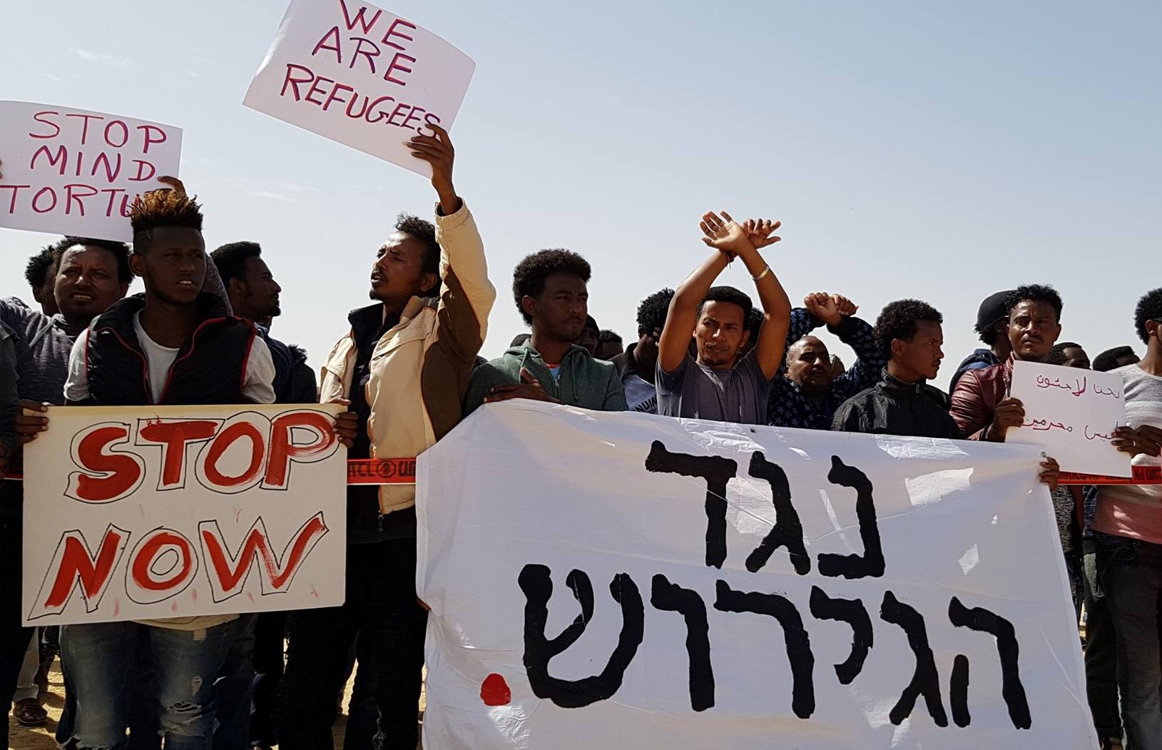 African asylum seekers demonstrate in Tel Aviv against deportation, June 2018; the large banner in Hebrew reads "Against Deportation."