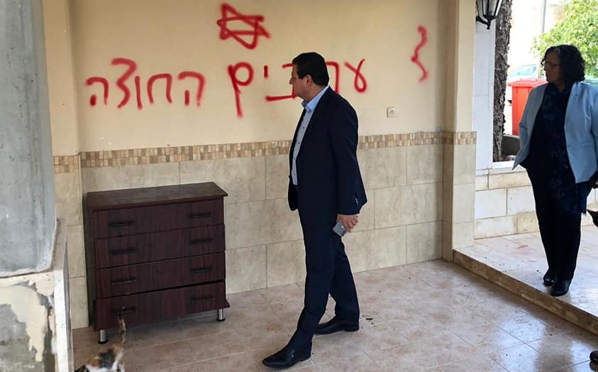 Echoes of another time, another place: Hadash MK's Ayman Odeh and Aida Touma-Sliman during a solidarity visit to the village of Manshiya Zabda on Thursday, December 12. The Hebrew graffiti spray painted on the wall reads: "Arabs out."