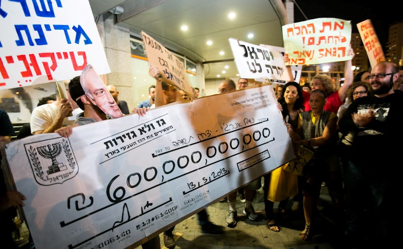 During a demonstration against the privatization of natural gas found in the Mediterranean Sea off the Israeli coast, protesters outside the home of the then Energy Minister, Silvan Shalom, hold up an oversized check (pun absolutely intended) from the State of Israel to Israeli tycoon Yitzhak Tshuva with the estimated value of the natural gas to eventually be produced from the Leviathan offshore natural gas field, May 11, 2013.
