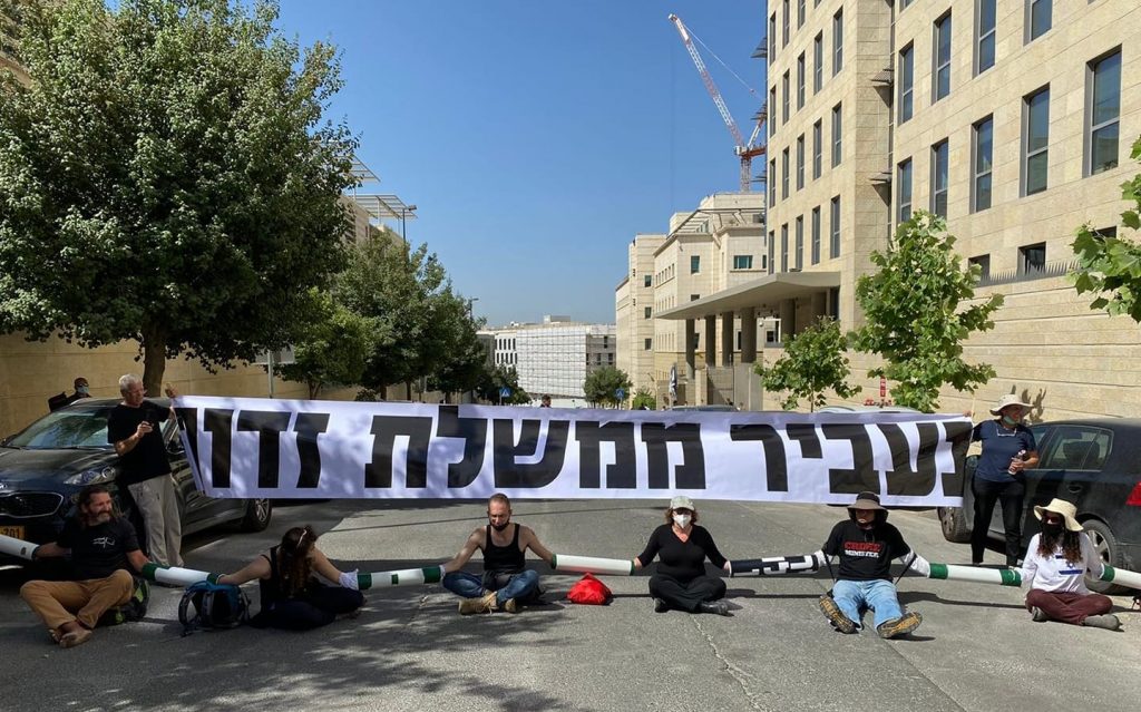 Demonstrators from the "Crime Minister" movement block the entrance to the offices of Israel's Foreign Ministry in Jerusalem, the venue of the weekly cabinet meeting, Sunday, June 7. The banner paraphrases a passage from a Jewish High Holiday prayer that speaks about "removing evil government" from the world.