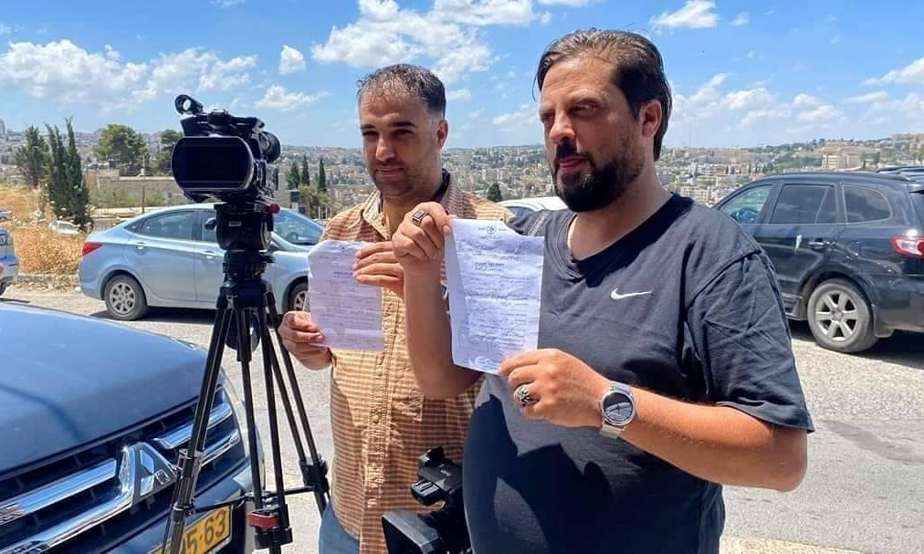 Palestinian TV crew members display orders issued by the Israeli police to report for questioning by law enforcement officers, June 3, 2020.