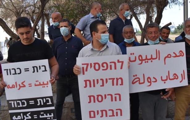 MK Ayman Odeh, center, participated in a demonstration held in Haifa on Thursday, July 2, against house demolitions in the northern Arab town of Nahef. The placard in Hebrew Odeh is holding reads: "Halt the Policy of House Demolitions." The sign at the right reads in Arabic: "House Demolitions are State Terror." The placard at the left reads in both Hebrew and Arabic: "Home = Dignity."