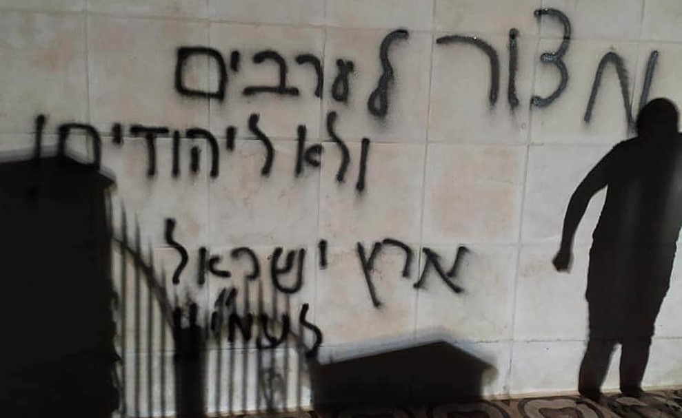Graffiti on an outer wall of the torched mosque in Al-Bireh reads "Siege on Arabs, not on Jews" and "the Land of Israel belongs to the people of Israel."