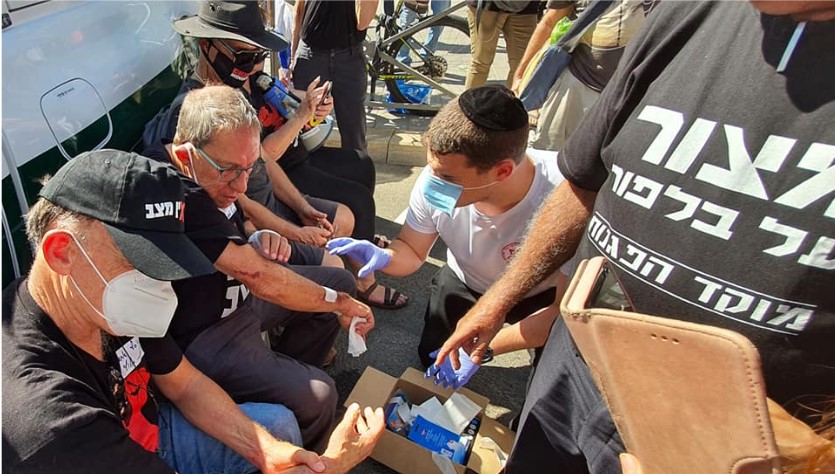 A paramedic treats Carmi Gillon, a former head of the Shin Bet security service, at the protest encampment outside the Prime Minister’s Residence in Jerusalem on Thursday August 20, 2020. Gillon’s hands and arms were scratched and bloodied in confrontations with police ordered to clear out the encampment to allow Netanyahu supporters demontrate there later in the day.