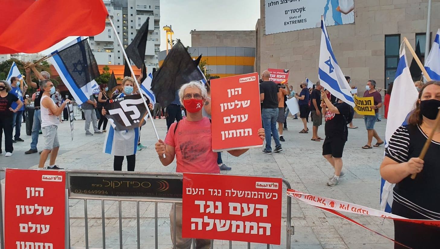 Demonstrators protest near the Mediatheque in Holon, last Saturday, October 24. The Hadash placard held by a Communist demonstrator reads: "Capital, Rule, and the Criminal Underworld"; the sign on the fence in front of him reads: "When the government is against the people, the people are against the government."