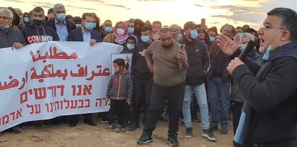 Hadash MK Youssef Jabareen (Joint List), right, addresses a protest held in the Negev against land expropriation, November 26, 2020. The white banner reads in Arabic and Hebrew: "Our Demand – Recognition of Our Ownership of Our Lands."