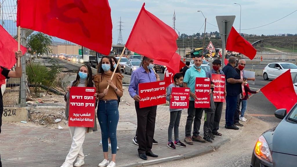 Hadash and Communist Party activists conduct a "red flag protest" in the Galilee. From left to right the Hadash placards read: "The people demand social justice"; "Netanyahu serves the wealthy"; "Salaried, independents, and unemployed together against the government"; "Democracy for all."