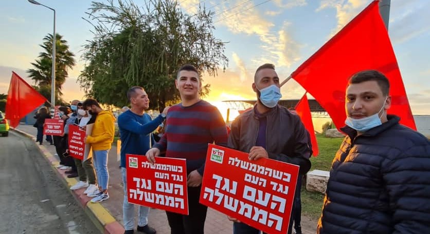 Members of Hadash hold a "Red flag protest" against Netanyahu near the Arab town of Taybe in the south of the Triangle region. The placards in the foreground read: "When the government is against the people, the people are against the government."