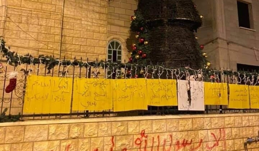 The second Christmas tree to be burned outside the Catholic church in Sakhnin this week; the graffiti sprayed in red paint on the stone wall reads: "Only Allah's Messenger Mohammed."