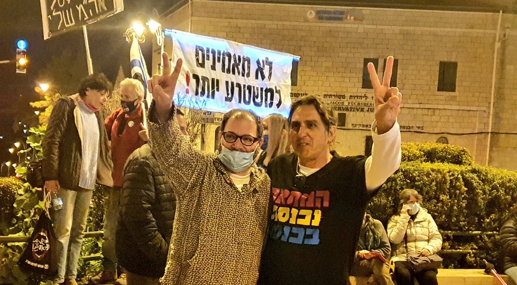 Hadash MK Ofer Cassif (Joint List, left) and leading protest activist Sadi Ben-Shitrit demonstrate near the official residence of the prime minister in Jerusalem’s Paris Square, Saturday evening, February 13, calling for Netanyahu’s resignation. The banner held up in the background reads “We no longer believe this evil regime!”