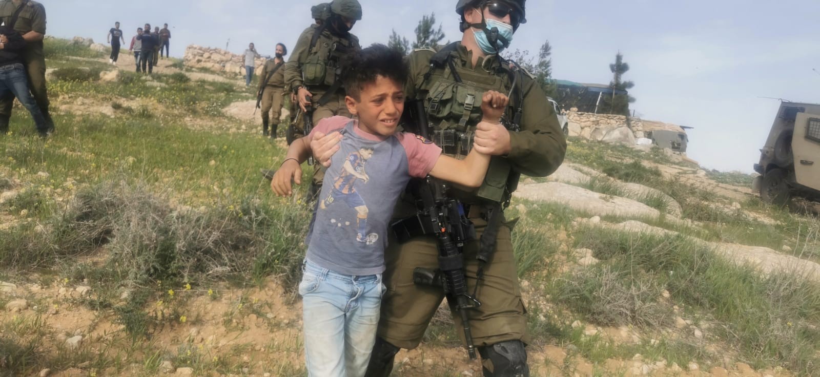 An Israeli soldier detains a Palestinian child close to al-Rakiz in the south Hebron hills, Wednesday, March 10, 2021.
