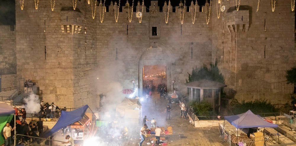 The smoke from the explosion of stun grenades hovers over the Damascus Gate plaza in occupied East Jerusalem, May 9, 2021.