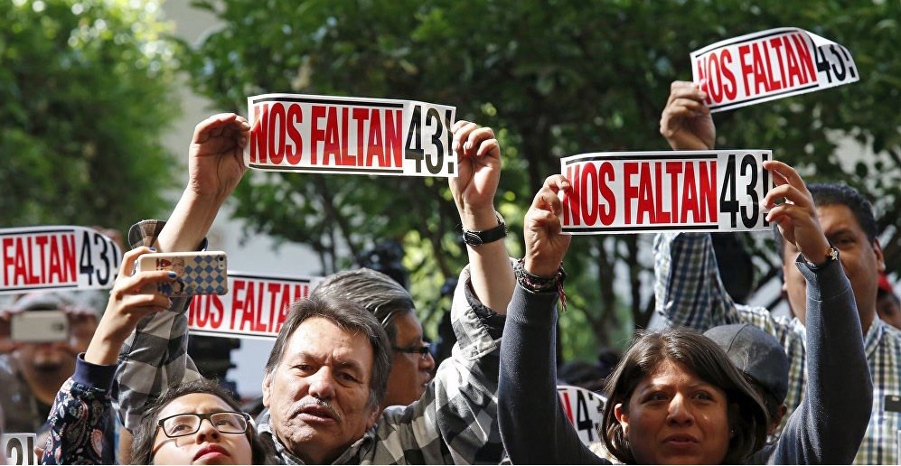 Relatives hold bumper stickers reading "We are missing 43," reference to the students from the Ayotzinapa Rural Teachers' College who were politically abducted in 2014 and presumably murdered. Tomas Zeron, residing in Israel since 2019, is wanted by Mexico for allegedly compromising the investigation into the student's disappearance as well as on charges of embezzlement.