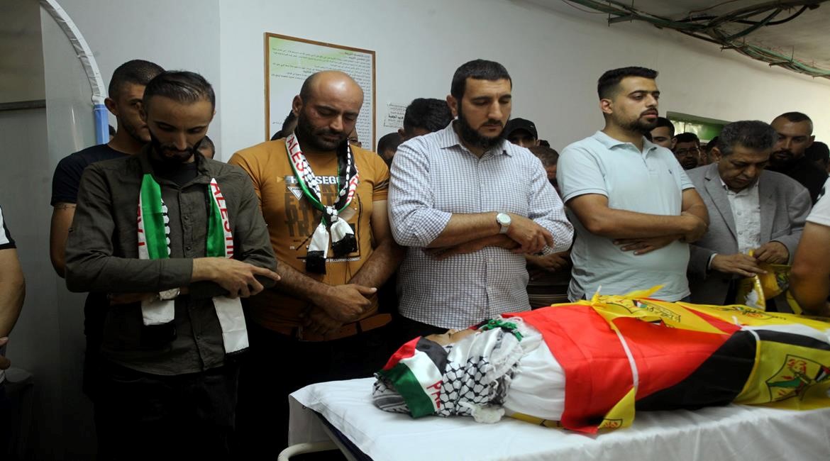 Just before the funeral procession during which confrontations erupted, mourners pray over thd body of 11-year-old Mohammad al-Alaama, resident of Beit Ummar, killed by Israeli soldiers, Wednesday, July 28, 2021. Because of the gunfire from the occupation forces, during which Shawkat Khalil Awad, 20, was mortally wounded, Mohammad's body was temporarily abandoned at the grave side until the funeral's attendees could return to give him an improvised, provisional burial.