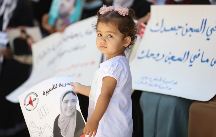 Palestinian women in Ramallah rally for the release of Anhar Al-Deek so that she can deliver her baby outside prison. The sign in Arabic to the right of the photograph reads in part: "Your body is in prison, but your spirit is not locked up…"