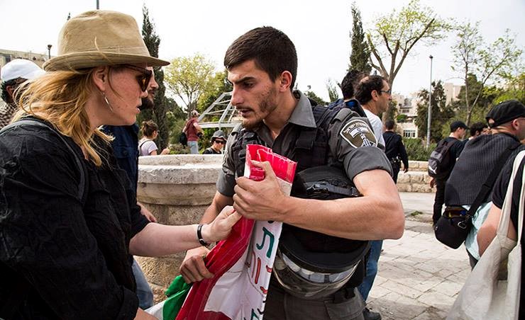 A border policeman confiscates a Palestinian flag from an Israeli demonstrator in occupied East Jerusalem's Sheikh Jarrah neighborhood, March 2015.