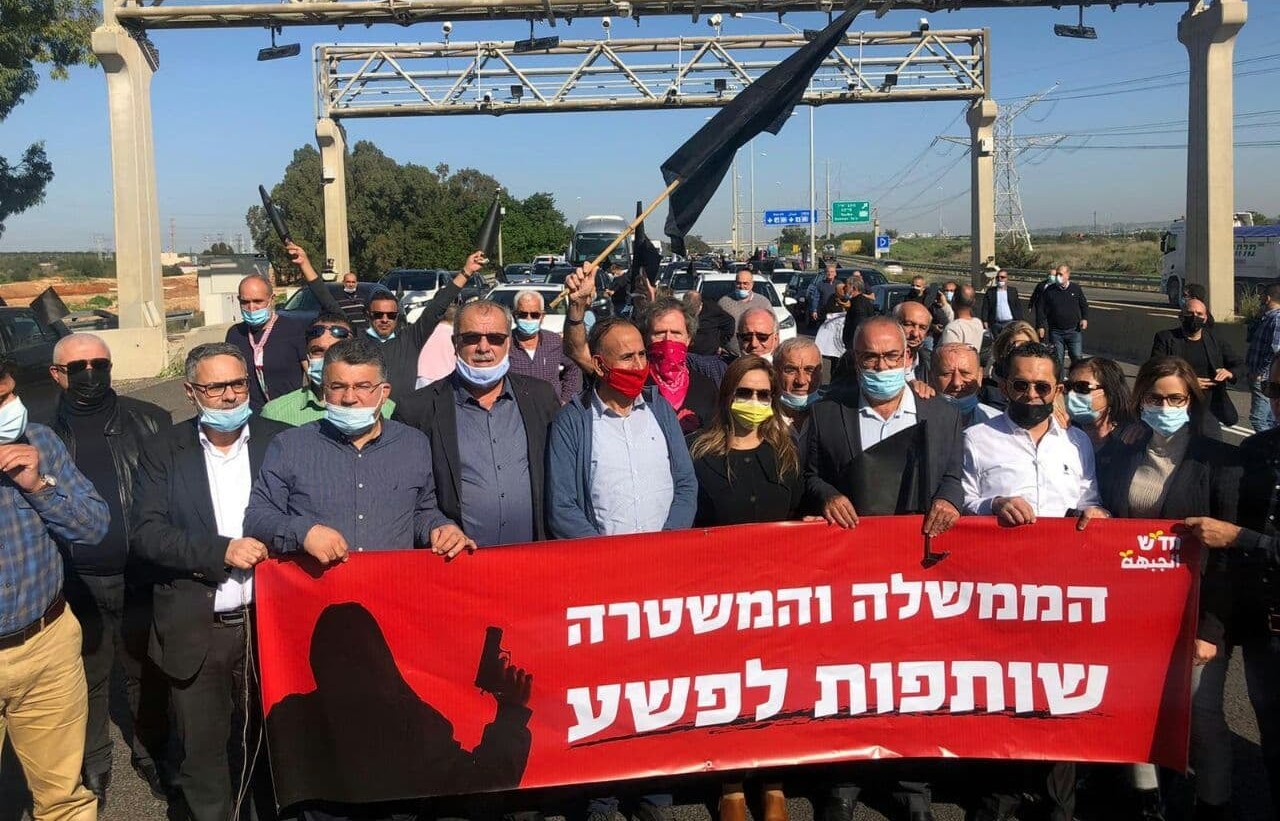 Leaders and members of Israel's Arab-Palestinian minority protest along Highway 6, the country's major north-south toll road, government inaction in the fight against criminal violence in Arab Society, February 2021. The red banner reads in Hebrew: "The government and police are partners in the crime."