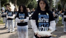 Animal right activists stand with dead bodies of chickens in their hands, wearing a T-shirt that reads: "Their lives are in your hands". The performance called to close and boycott the meat company "Zoglovek" after an investigation revealed harsh animal treatment in the company's meat production, Tel-Aviv, November 1, 2013. (Photo: Activestills)