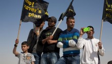 Arab-Bedouins and other activists participating in a vigil to mark Land Day in the unrecognized village of Wadi El Naam, Israel, on March 30, 2012. During the vigil the protesters held signs calling to stop Prawer Plan, approved by the Israeli government on the 11th of September, 2011. The plan will displace more than 40,000 Arab-Bedouin citizens through the destruction of most unrecognized Bedouin villages in the Negev desert (Photo: Activestills)