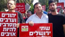 Hadash MKs Dov Khenin, left, and Ayman Odeh (Chair of the Joint List), center, in a demonstration held in Central Tel Aviv on October 9, 2015. Khenin's placards reads: "Jews and Arabs refuse to be enemies."