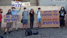 Demonstrators express solidarity with Hallel Rabin (center, wearing black) outside the Tel Hashomer military induction center near Tel Aviv, October 21, 2020. The large placard at the right reads: "Not as a clerk and not in a tank – Rather a refuser and feminist"; at the left the sign held aloft reads "End the occupation"; and the placard below it reads: "Refusal is democracy."