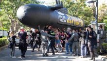 Police and demonstrators scuffle on Friday afternoon, December 25, near the private residence of Benjamin Netanyahu in Caesarea. The banner on the plastic submarine reads: "No Absolution – Investigate Now."
